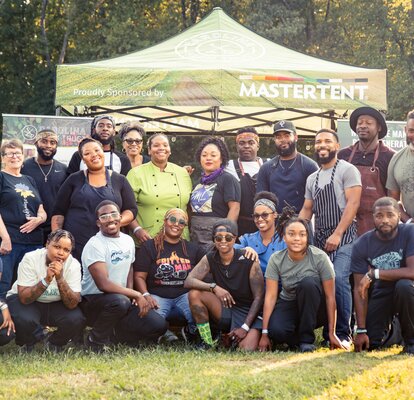 A group of people posed in front of a sponsored non-profit Mastertent.