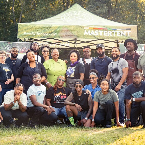 A group of people posed in front of a sponsored non-profit Mastertent.