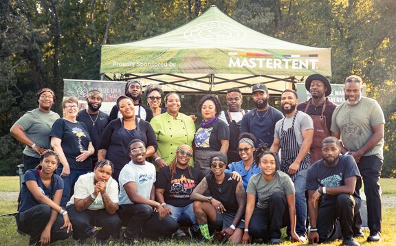 A group of people posed in front of a sponsored non-profit Mastertent.