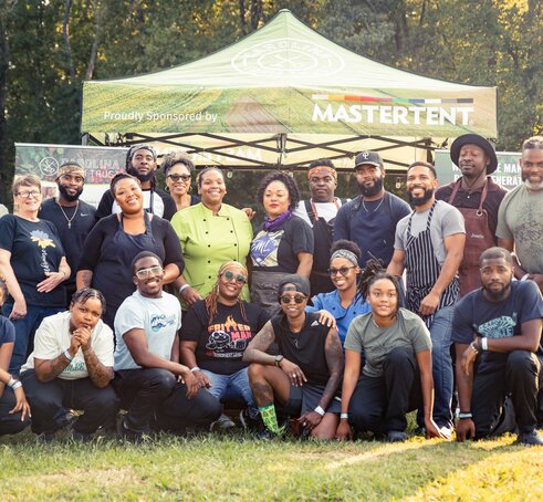 A group of people posed in front of a sponsored non-profit Mastertent.