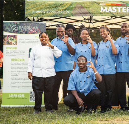 A group of catering chefs stand in front of a custom 10x10 canopy tent. 