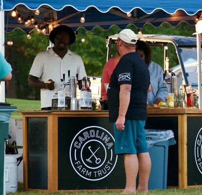 A custom canopy tent stands above a bar and serves event guests. 