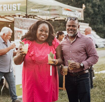 Event visitors stand in front of a green, Carolina Farm Trust custom 10x10 canopy tent. 