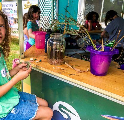 A Catawba Riverkeeper visitor sits at the counter of an outdoor, mobile Mastertent pavilion. 