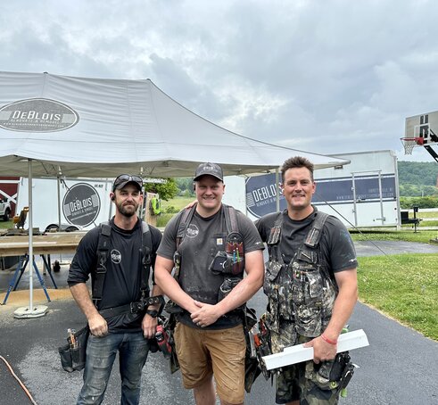 Renovation team standing in front of heavy duty Mastertent brand work tent outside at a job site. 