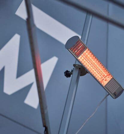 A mobile, infrared heater mounted on the interior mast of a Mastertent event tent.