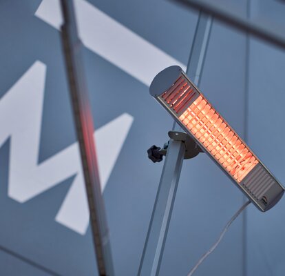 A mobile, infrared heater mounted on the interior mast of a Mastertent event tent.