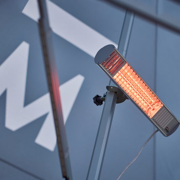 A mobile, infrared heater mounted on the interior mast of a Mastertent event tent.