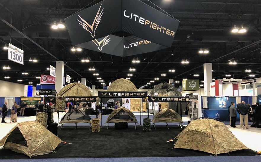 A retailer sells camping tents using a 10x10 custom canopy tent at a trade show. 