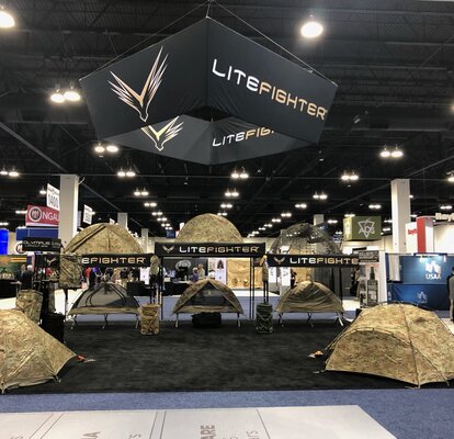 A retailer sells camping tents using a 10x10 custom canopy tent at a trade show. 