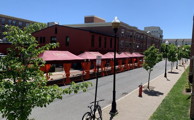A row of Mastertent Series 1 20x10 canopy tents arranged in a multi-tent system for outdoor dining. Bordeaux roof and orange corner curtains branded for Delta's Restaurant.