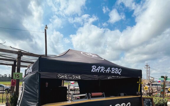 A black, 15x10 Mastertent canopy tent with wrap-around walls and serving counter. Branded for Bar-A-BBQ barbecue company.