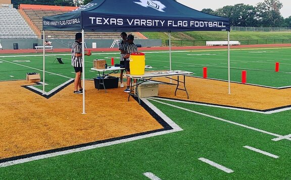 A 10x10ft Mastertent canopy tent set up on a football field for a flag football game.