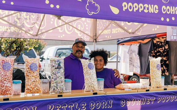 A purple 10x10ft printed canopy tent with counters to sell popcorn.