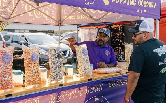 A purple 10x10ft printed canopy tent with counters to sell popcorn.