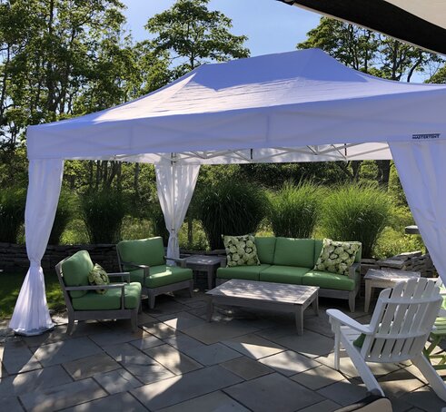 A 15x10 white canopy tent with a white frame creates shade above a backyard patio. 