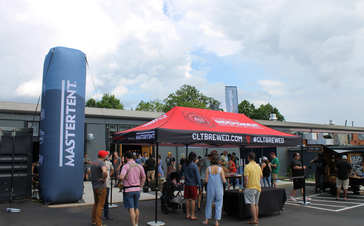 Posed next to a custom event inflatable, a custom 20x10 event tent shades event goers as they taste different beers from breweries. This tent has a custom colored tent frame and custom printing. 