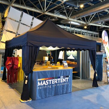A 17x17 trade show tent indoors with canopy curtains and tent ceiling. 