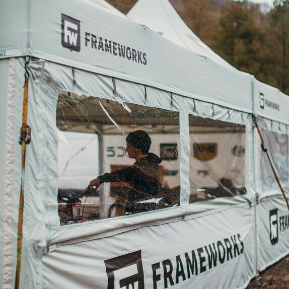 A 17x17 custom tent built for mountain biking with grey fabric, custom window fabrication, sidewalls and logo printing. 