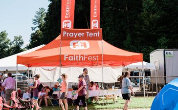 Event and concert attendees sit underneath a custom orange 20x13 Mastertent canopy tent.