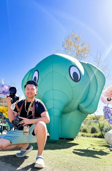 A photographer posing in front of a green custom inflatable elephant at Sabaidee Fest. | © @chueleephotodesign