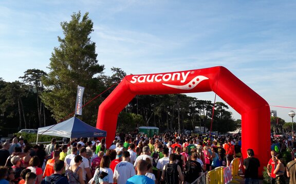 Crowd races under red Mastertent brand inflatable arch structure. 