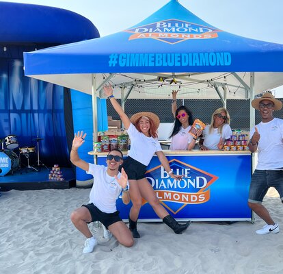 Crowd pose for picture on the sand under Blue Diamond branded Mastertent square pavilion.