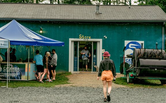 Crowd taking shelter from the rain under a Catawba Riverkeeper branded pavilion. 