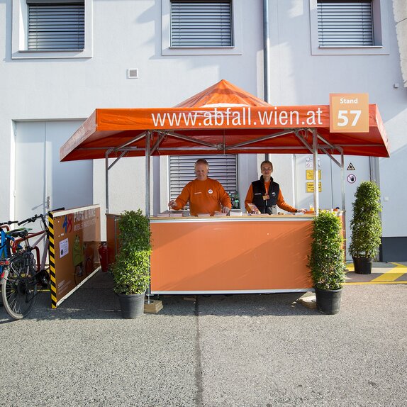 Orange hexagonal pavilion with smiling attendants. 