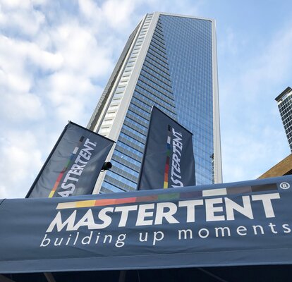 A close up view of Mastertent canopy tents and flags and Charlotte, NC skyscrapers.