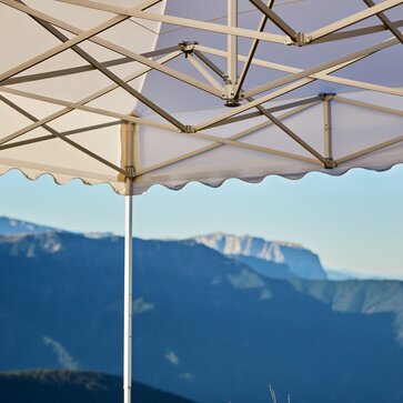 underneath view of a 17x17 pagoda tent aluminum frame structure with a white roof in a field with mountains in the background