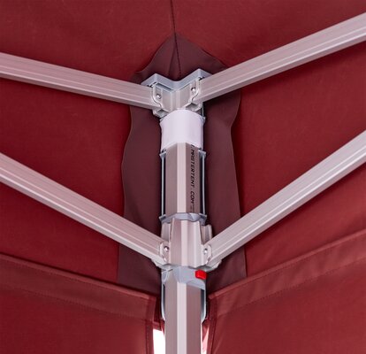 Inside view of an aluminum corner of a canopy tent frame with burgundy fabric wrapped around the top and outside