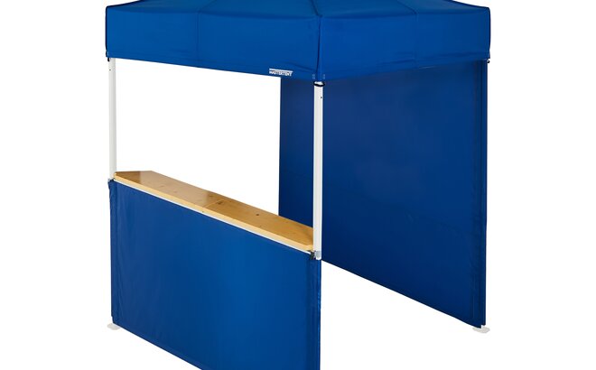 A blue 6.5x6.5ft Mastertent with two blue fabric sidewalls. One sidewall is closed and one is a half-height with a wooden counter. 