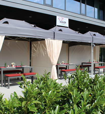 Die Terrasse vor dem Restaurant ist mit drei Faltzelten überdacht. Darunter befinden sich gedeckte Tische für die Gäste.