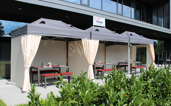 La terrazza di fronte al ristorante è coperta da tre gazebo pieghevoli. Sotto di loro ci sono delle tavole imbandite per gli ospiti.