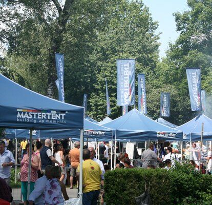 Blaue Faltpavillons überdachen die Gäste beim Donaupark Gulaschfestival in Wien.