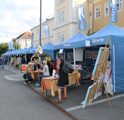 Die blaue MASTERTENT Faltpavillons mit Seitenwänden stehen in einer Reihe und fungieren als Verkaufszelte.