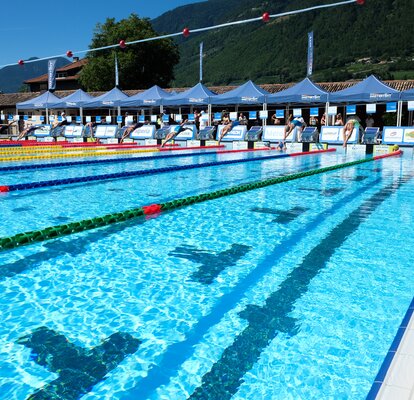 Eine Schwimmerin, mit einer weißen Badehaube und schwarzen Badeanzug, schwimmt Richtung Ziel.