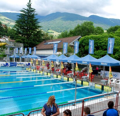 Das Bild zeigt ein Schwimmbad mit 9 Rennbahnen und blauen MASTERTENT Faltpavillons als Unterstand für die Schiedsrichter.