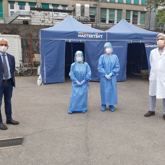 2 paramedics, 1 doctor and a coordinator stand in front of a blue Mastertent folding tent. 