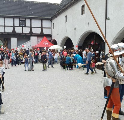 Der rote Faltpavillon vom EuregioFamilyPass inmitten einer Veranstaltung. Vorne steht ein Ritter.