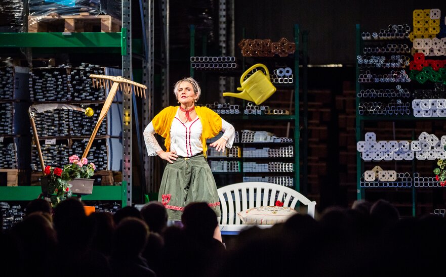 The actress Ingrid Maria Lechner is standing on the stage and performing a drama with different utensils.