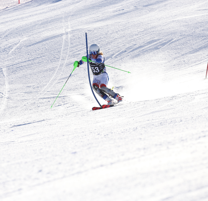 Die Rennläuferin befindet sich im Slalom bei einer blauen Kippstange.