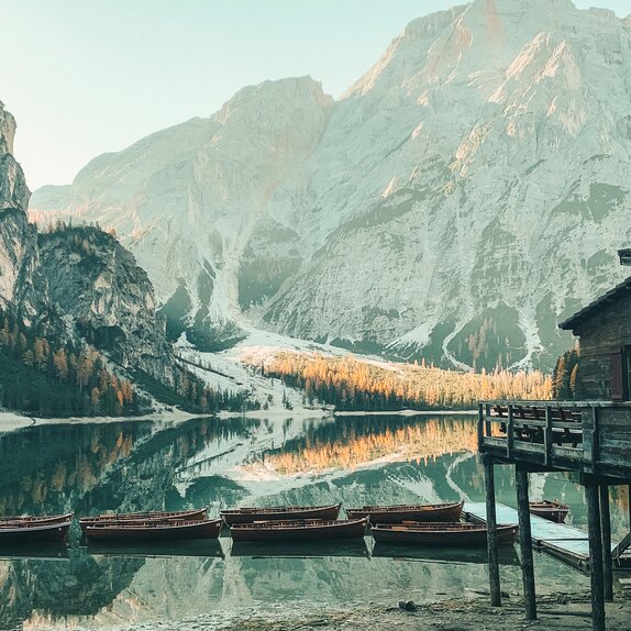 Braies Wild Lake with the cottage and its boats. Behind it mountains are glowing.