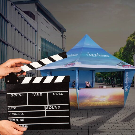 A woman is holding a flap in front of the promotion tent. The promotion tent is standing in the dark and is illuminated.