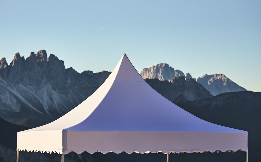 Il tetto bianco del gazebo pagoda con il frontalino ondulato. Nello sfondo si vedono le montagne.