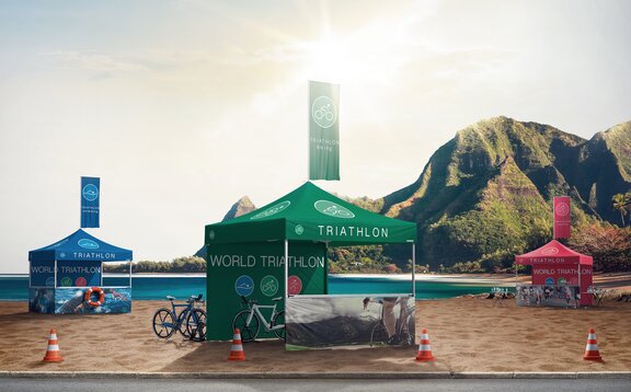 3 gazebos during a sport event. The gazebos are green, blue and red. All of them have a flag on the roof. 