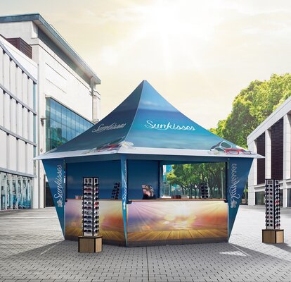 Das Promotionzelt für Sonnenbrillen steht in der Einkaufsstraße. Der Faltpavillon ist und blau und vollflächig bedruckt. 