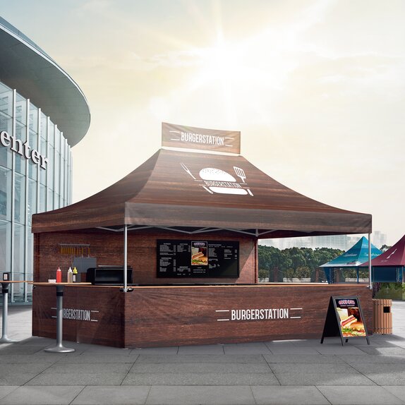 Brauner Faltpavillon mit vollflächiger Bedruckung als Burgerstand. Er steht vor einer Messe.