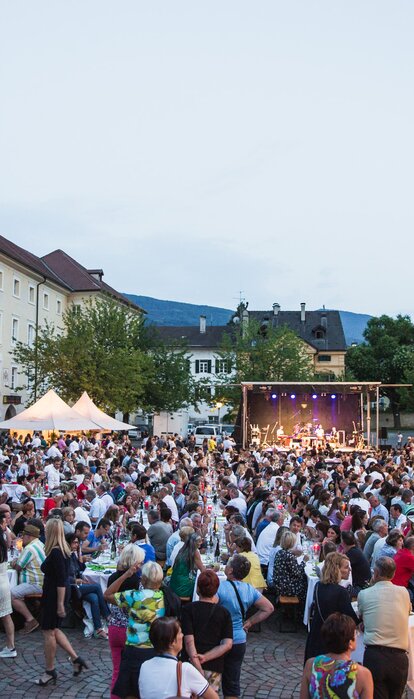 Diversi gazebo per eventi nella piazza del Duomo di Bressanone al Dine & Wine festival. La gente è seduta e festeggia.